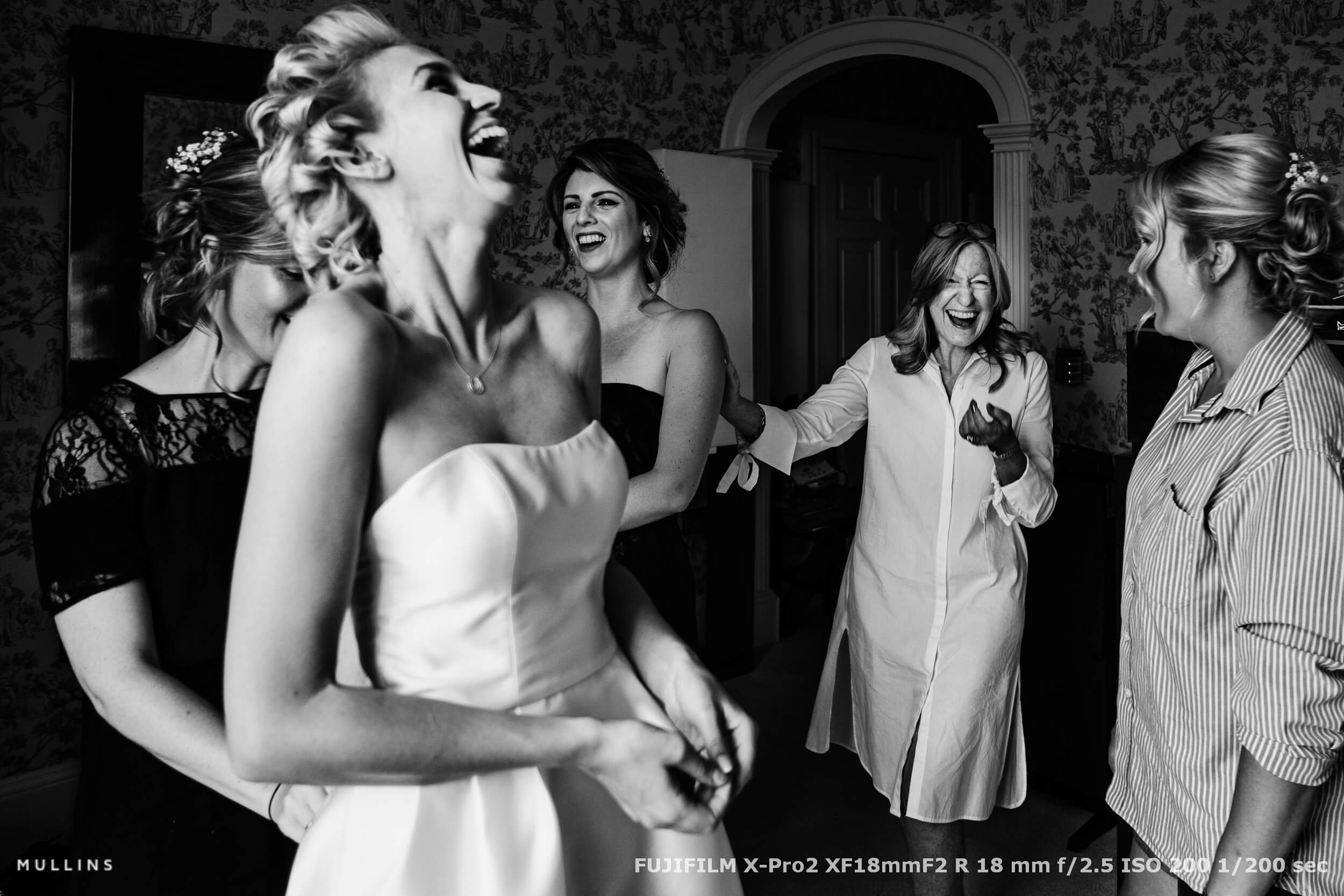 Bride and bridesmaids laughing together during morning preparations, captured candidly in the energy of the moment